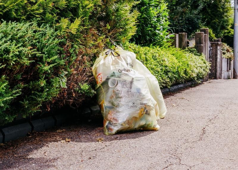 Neue Abfuhrtage der Gelben Säcke. Zwei gelbe Säcke stehen auf einem Gehweg.