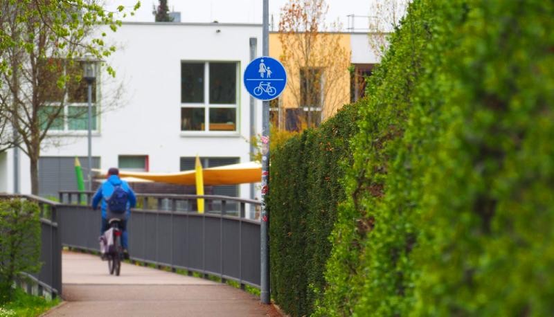 Stadtradeln 2026 in Süßen Ein Mann radelt über eine Brücke in Richtung eines Flachdachbaus.
